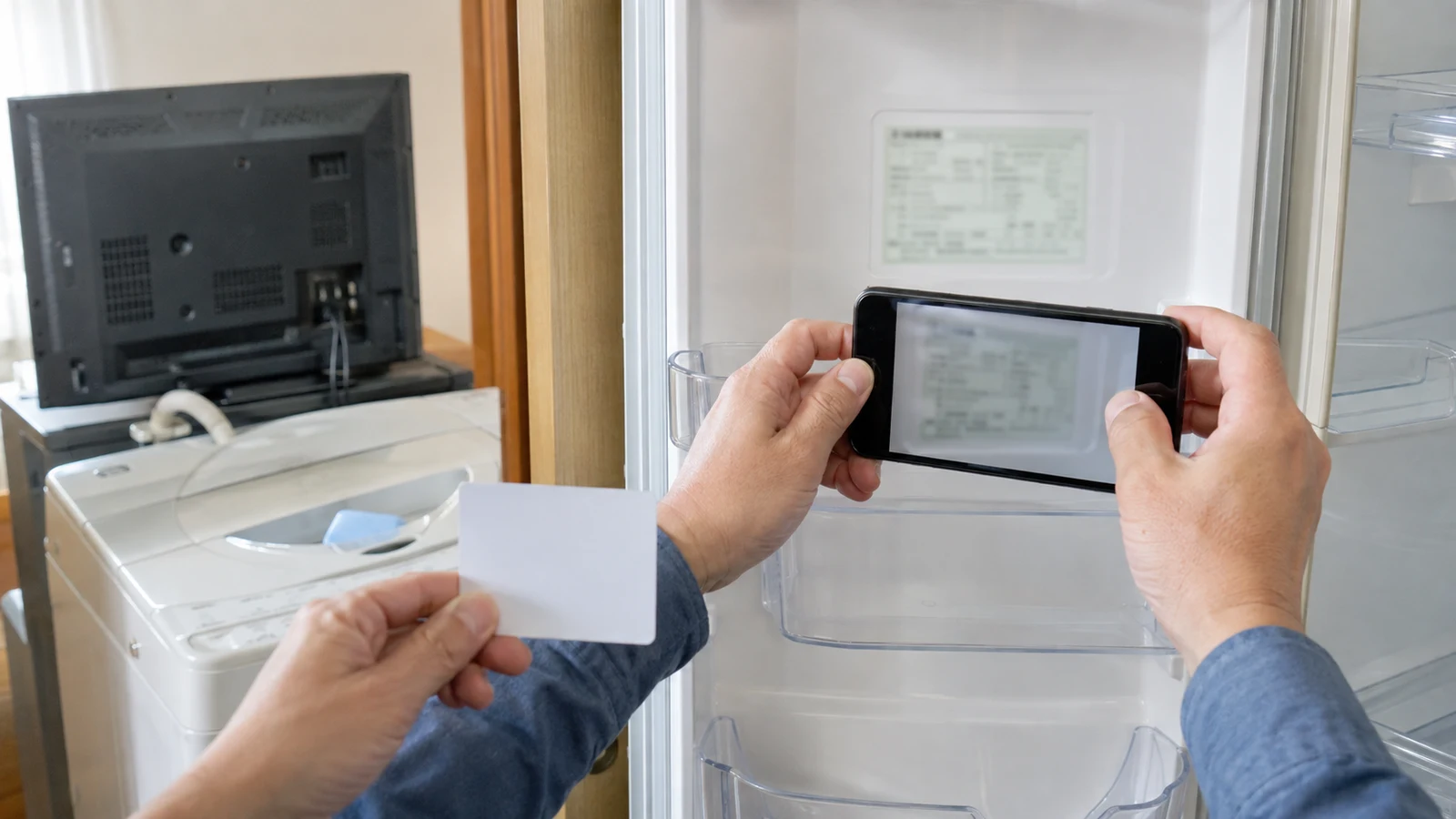 利用者が冷蔵庫の本体ラベルをスマートフォンで撮影し、製造業者、型番、定格内容積を家電リサイクル券の案内と照合している。