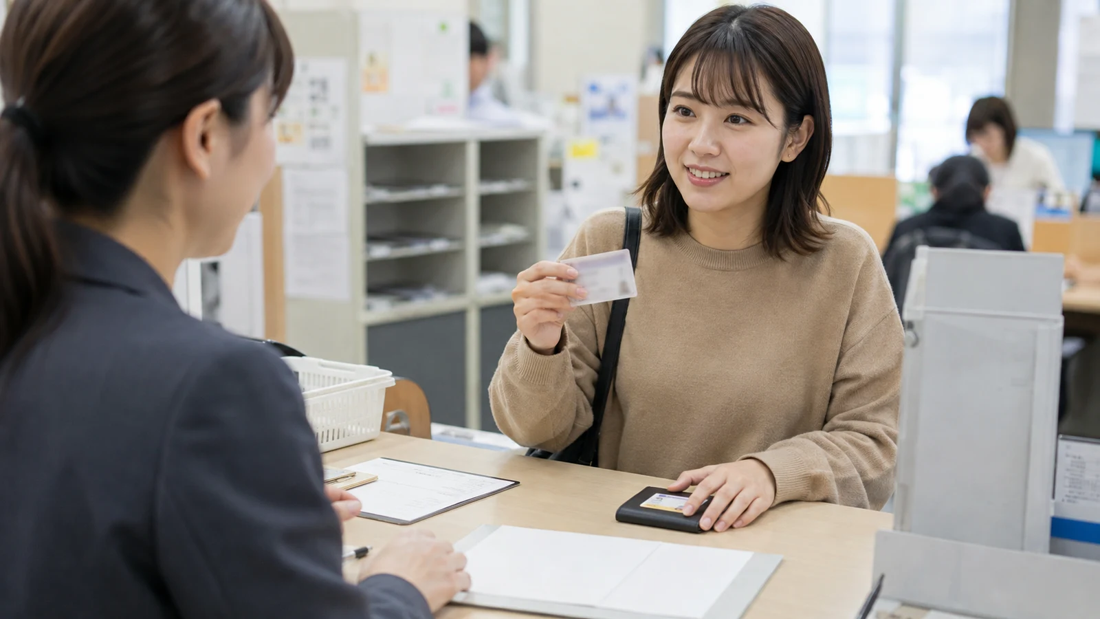転居した人が市区町村窓口で住所変更手続を行い、必要書類とマイナンバーカードを担当者と確認している。