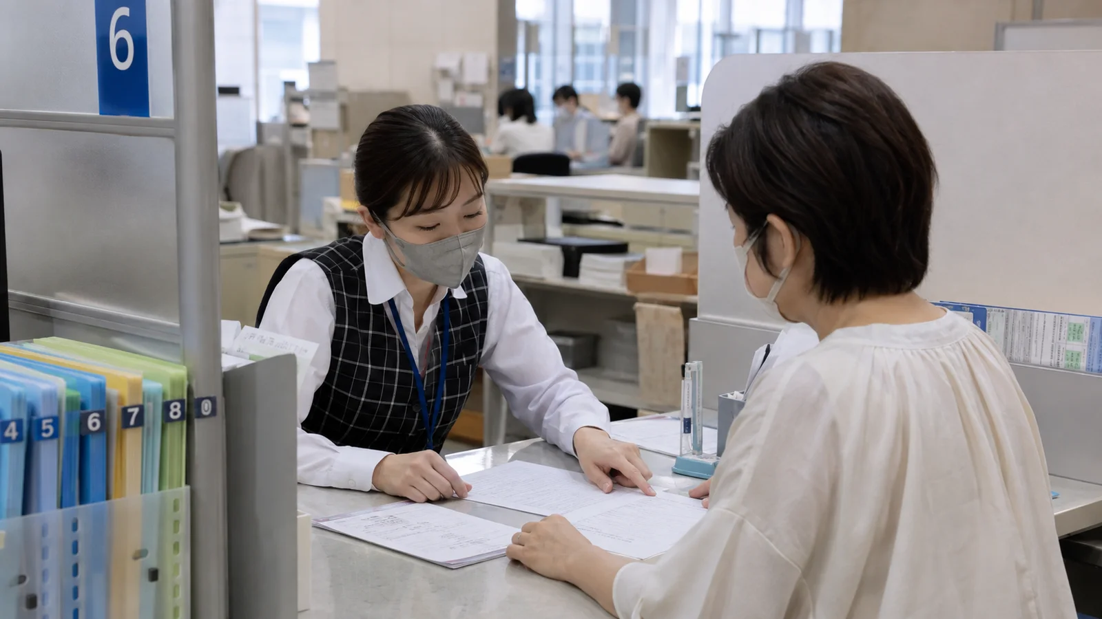 市区町村窓口で本人が戸籍証明と手続一覧を見ながら、担当者にフリガナ変更の経緯を確認している。