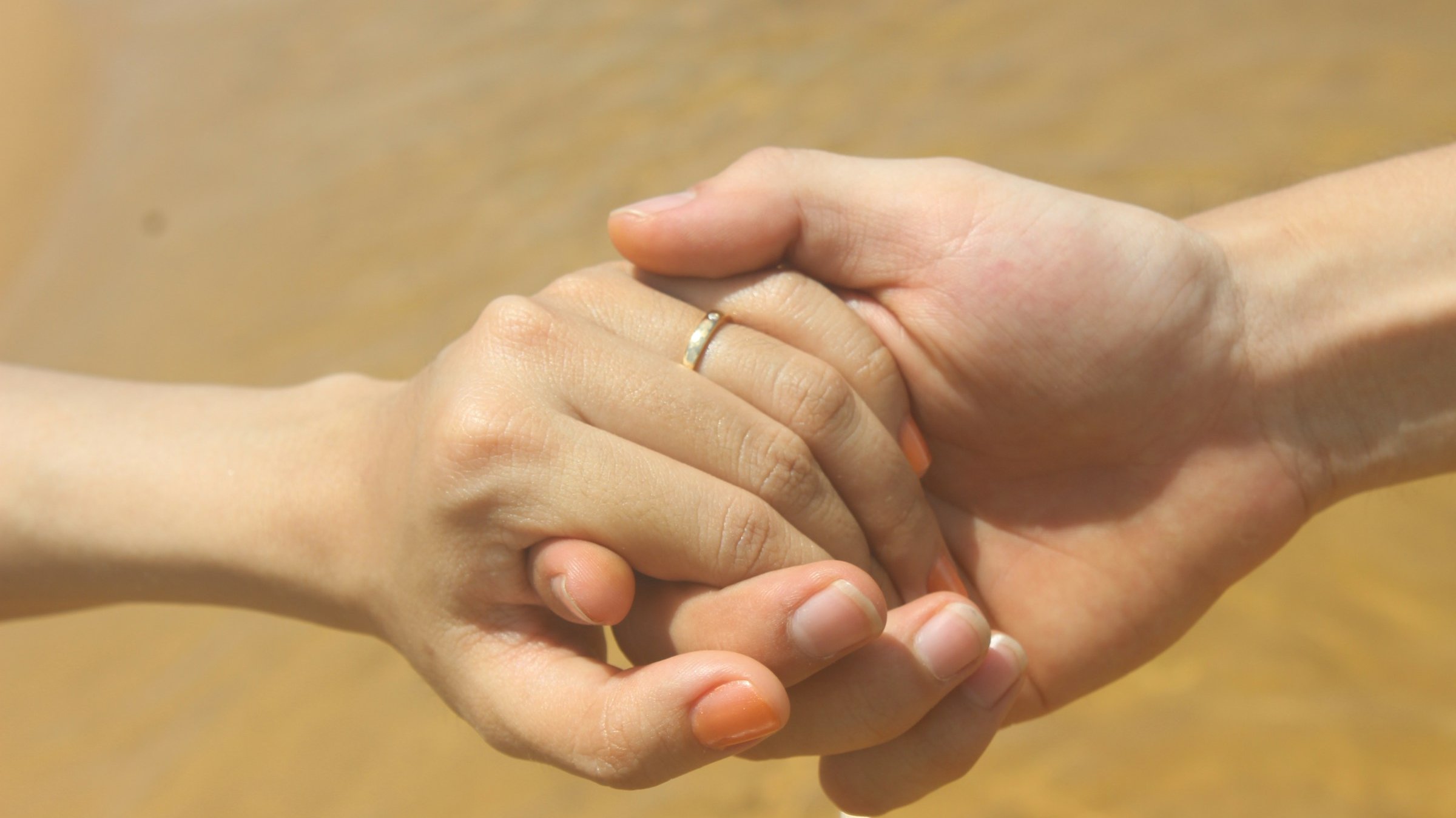 2人の手をつなぐクローズアップ。成婚=パートナーシップ成立の場面を象徴。