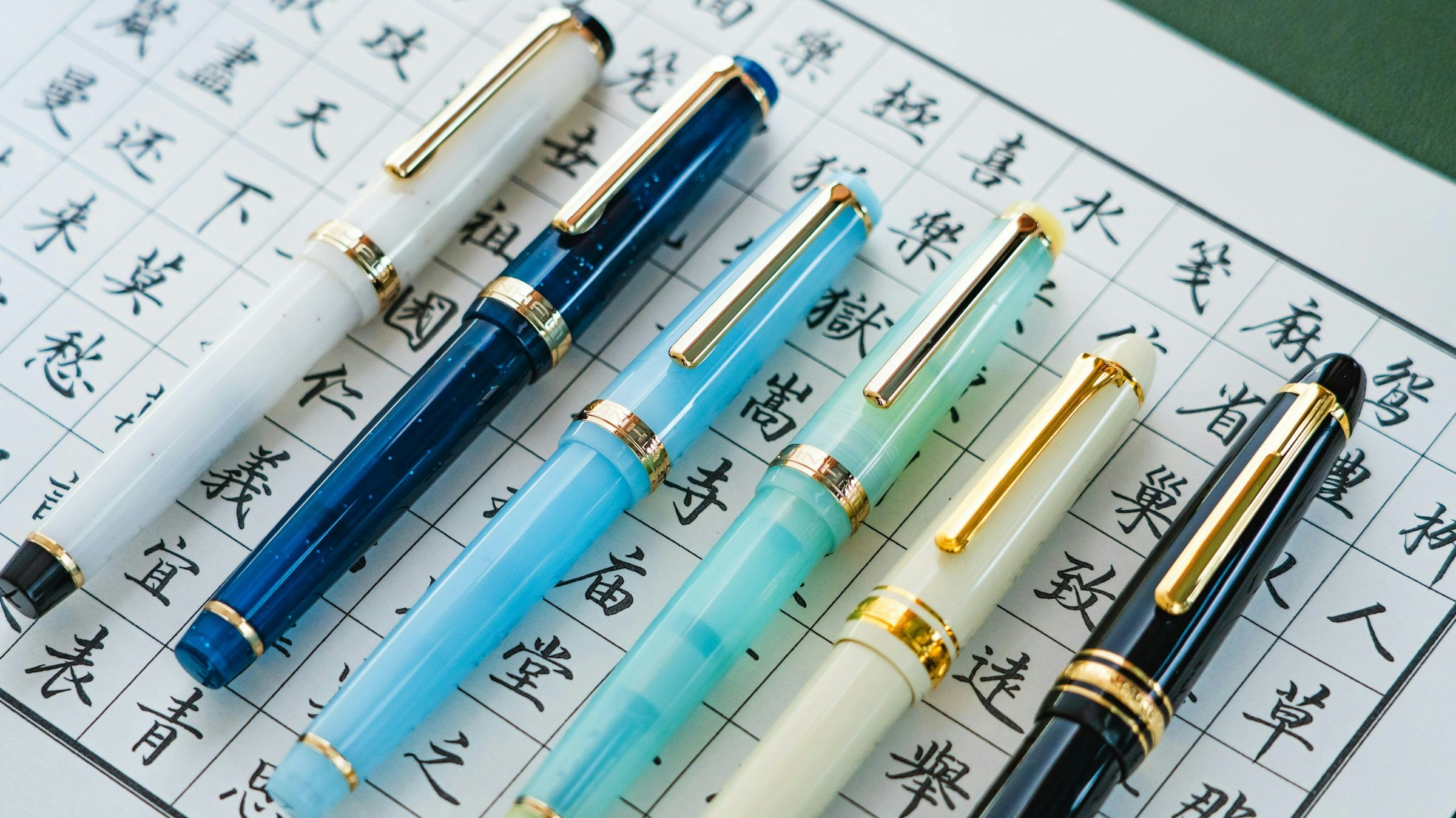複数の万年筆と漢字書類のフラットレイ。契約書事前確認・サインの場面を象徴。