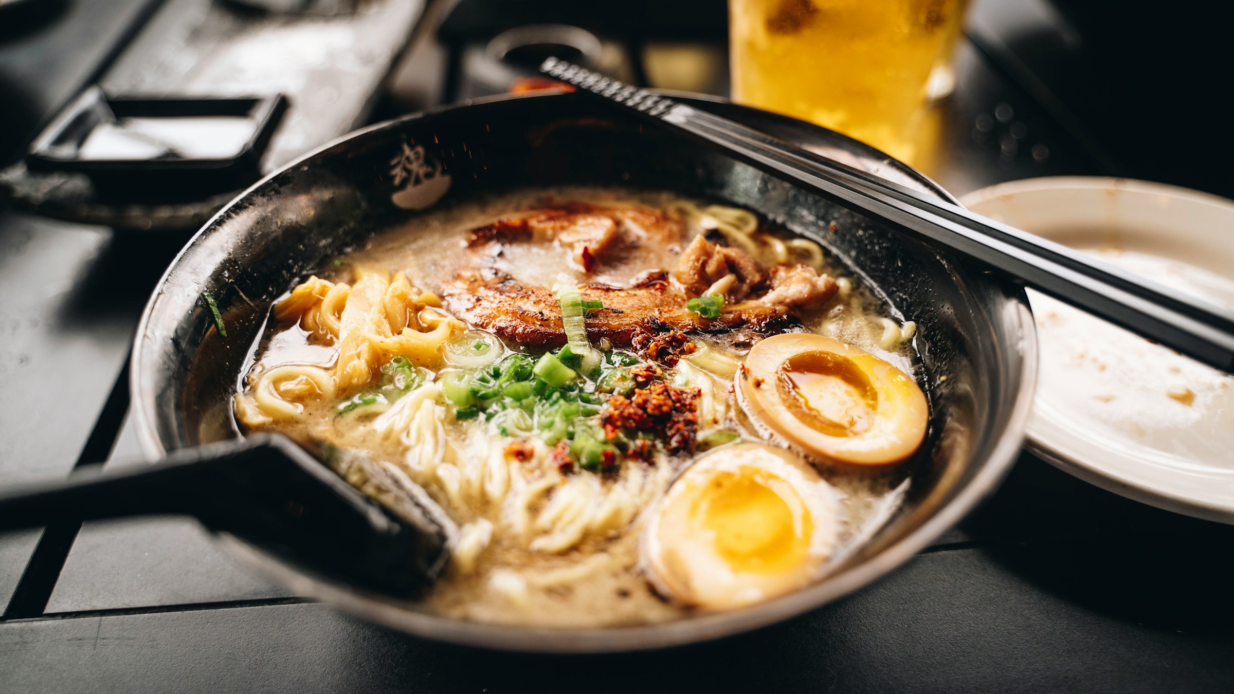 黒い金属丼に盛り付けられた一杯のラーメン。チャーシュー・煮卵・ネギ・薬味が層になって並ぶ、現代の専門店スタイルの一杯を象徴する一枚。