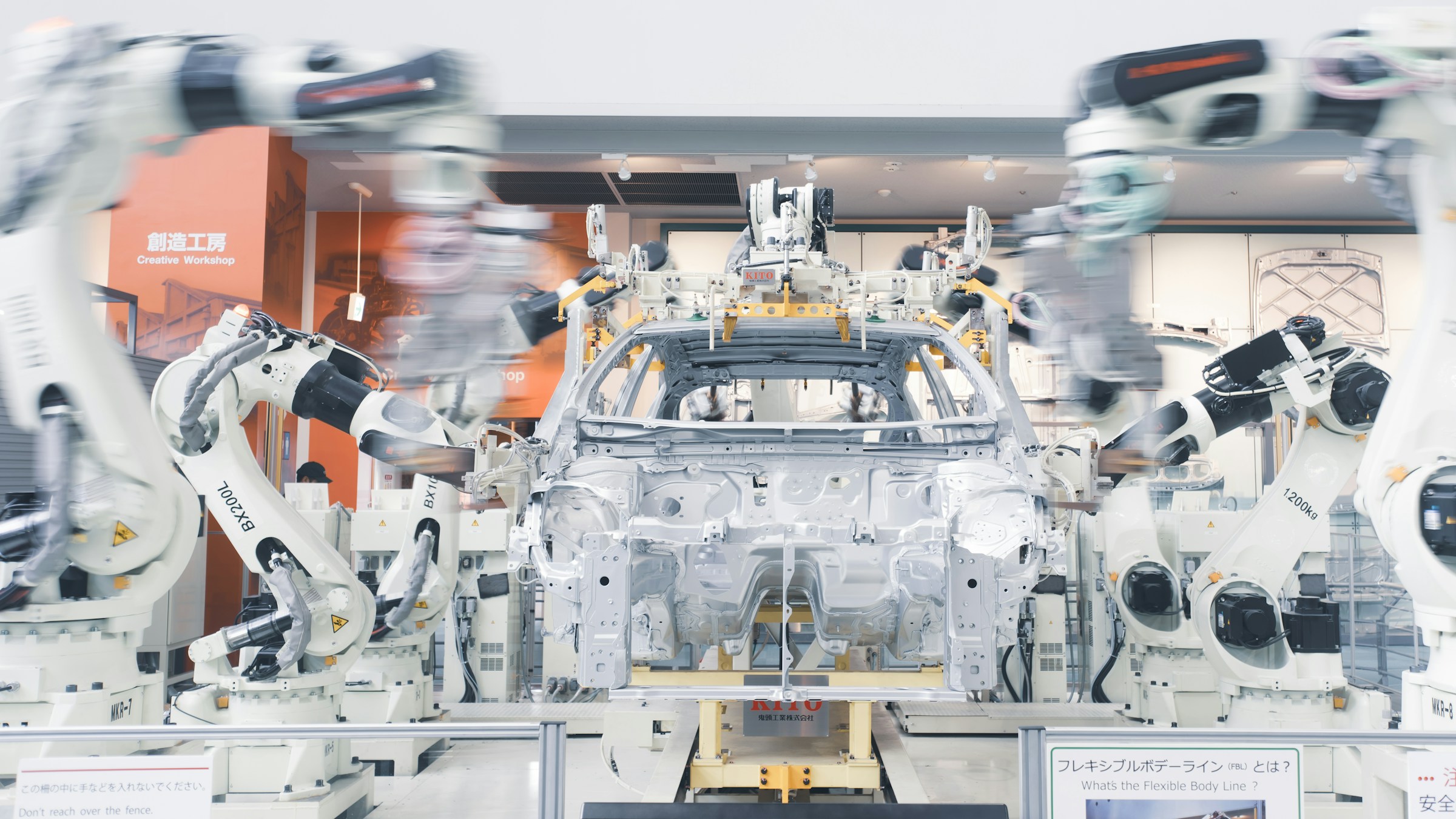自動車組立ラインで車体を組み立てるロボットアーム群。