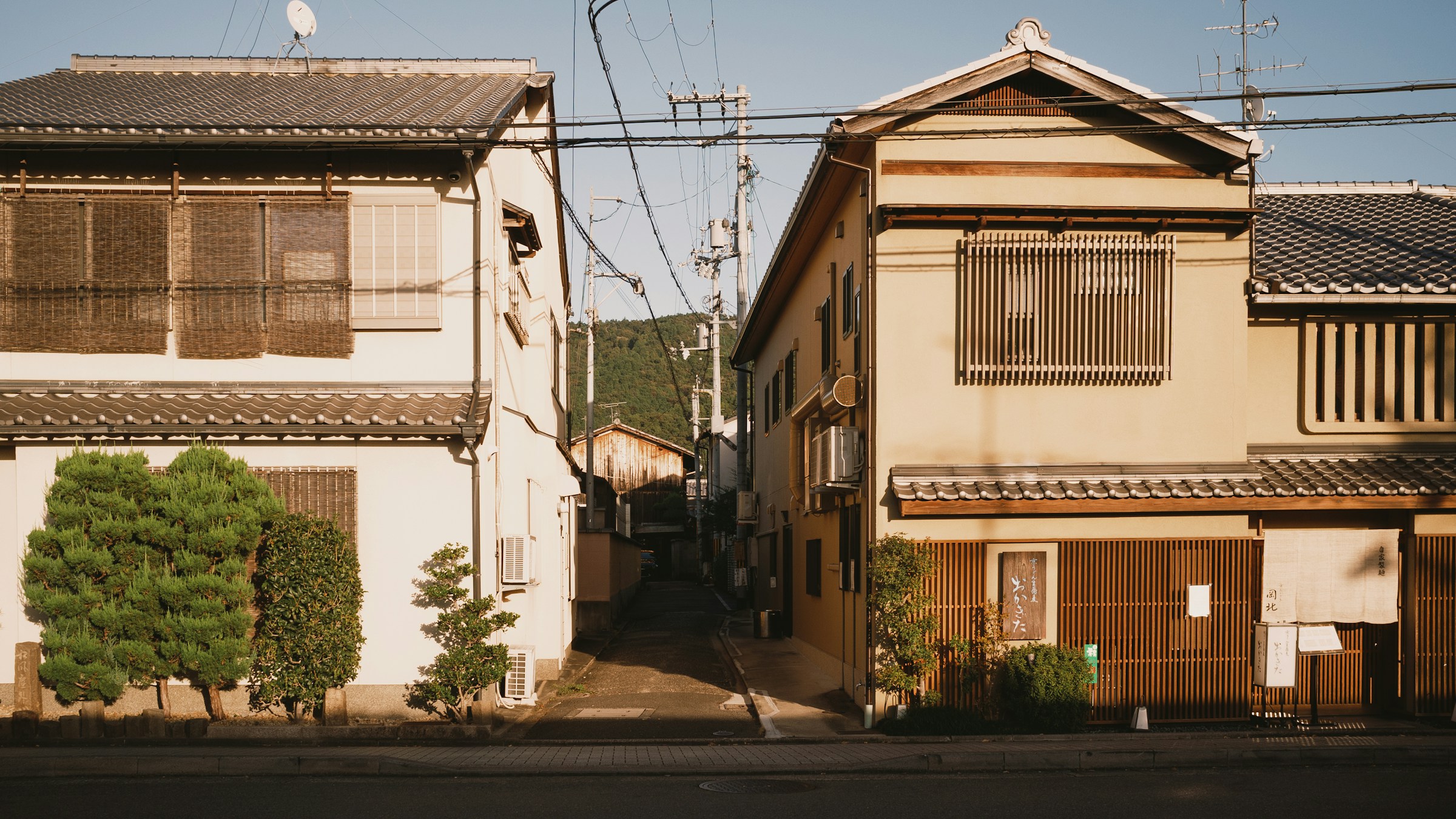 京都の住宅街。瓦屋根の家屋が向かい合う細い小道。