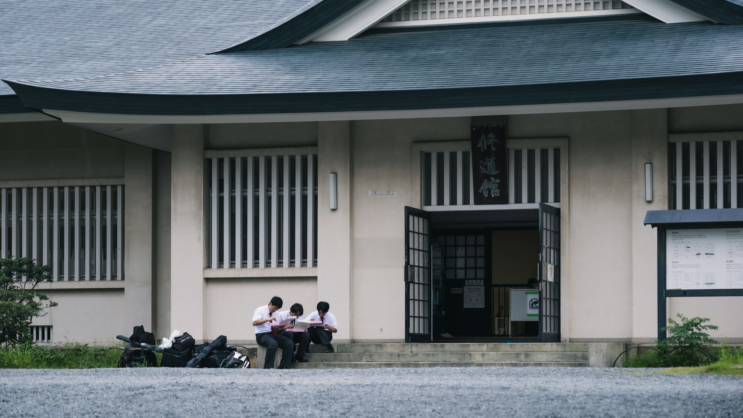 伝統的な日本の校舎の外で座る生徒たち。