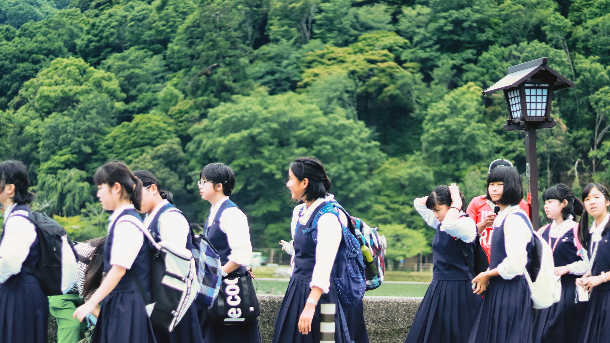 緑の校庭に立つ制服姿の女子生徒たち。
