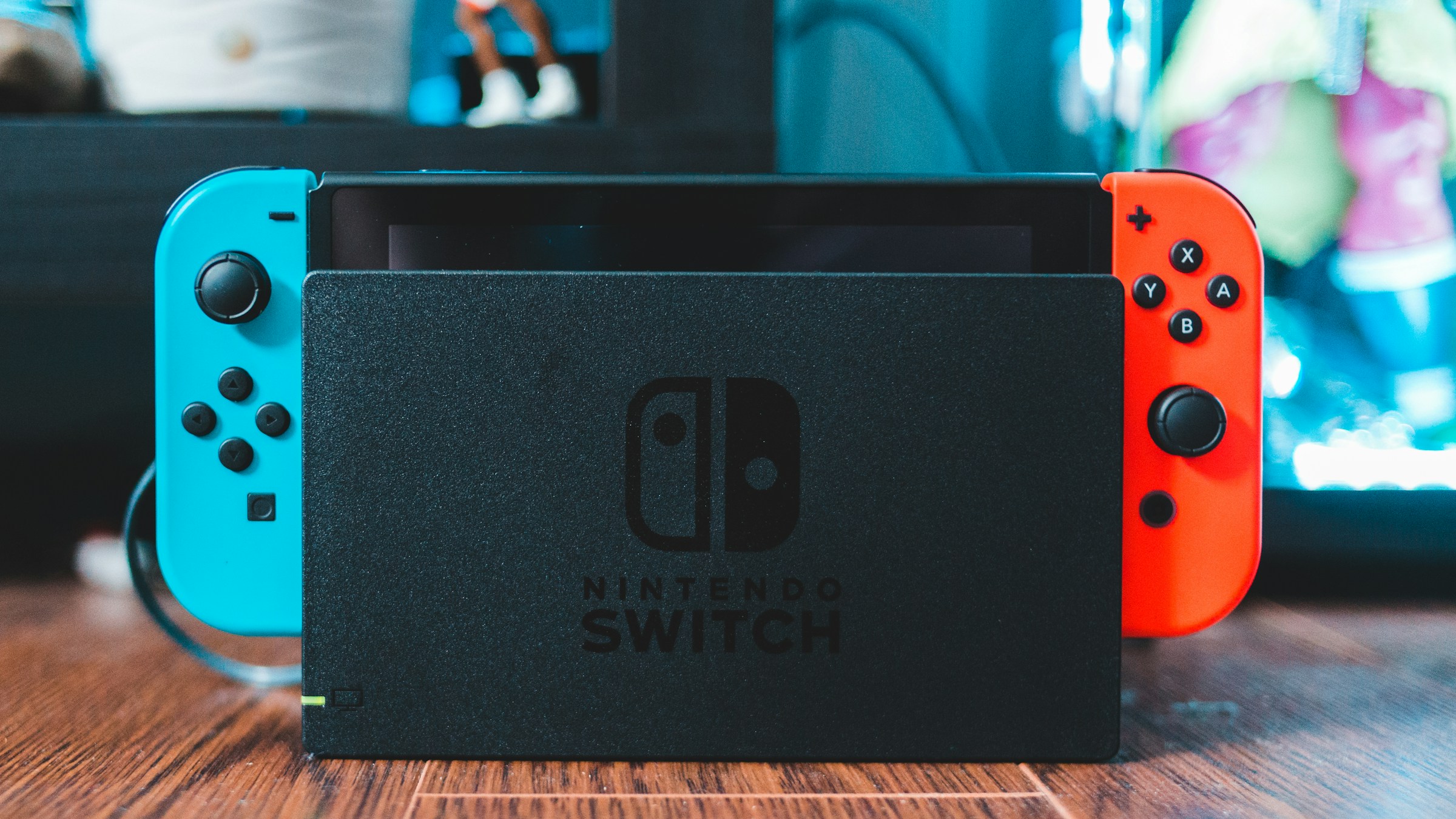 木のテーブルに置かれた、赤と青のJoy-Conを装着したNintendo Switch本体。