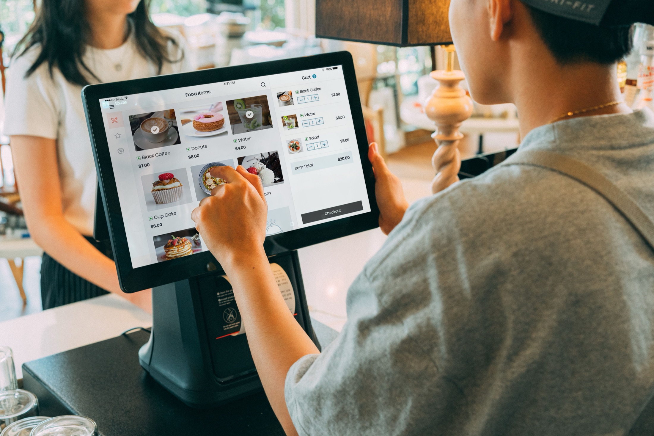 カフェのカウンターでタブレット型POSレジを操作するスタッフ