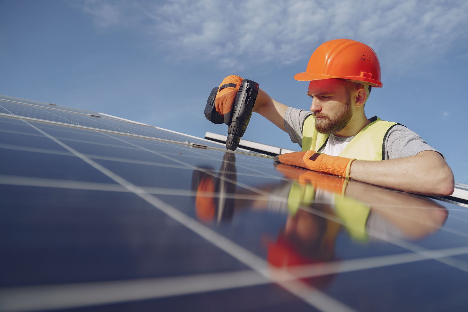 住宅の太陽光発電と蓄電設備の配線を施工する電気工事担当者