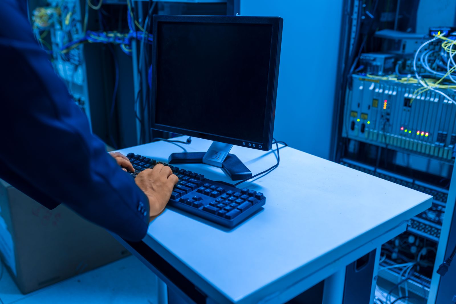 サーバールームでネットワーク機器の接続状態を点検する技術者